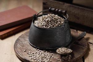 Sunflower seeds in measuring cup on the wooden background photo