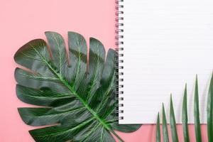 White diary book with green leaves on pink background photo