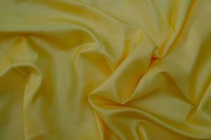 Primer plano de una elegante tela de seda amarilla suave textura de tela de lujo