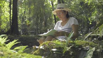 Female biologist taking note about natural data in tropical forest. video