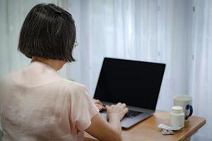 Senior mujer asiática buscar sobre salud y medicación desde internet foto