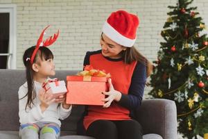 madre e hijo asiáticos abren juntos la caja de regalo de navidad foto