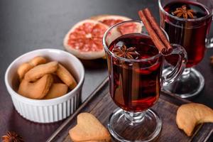 Navidad vino tinto caliente con especias y frutas sobre una mesa oscura. foto