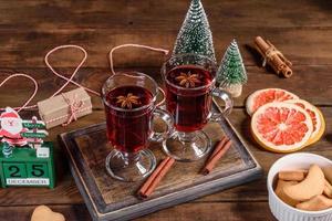 Navidad vino tinto caliente con especias y frutas sobre una mesa oscura. foto