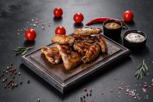 Grilled spicy chicken wings on a dark background with spices and herbs photo