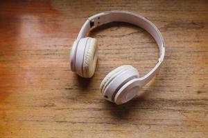 White headphones on wooden background. Music concept. photo