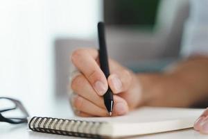 Manos de hombre escribiendo en el bloc de notas, cuaderno con bolígrafo foto