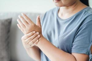 Woman sitting on sofa holds her wrist photo