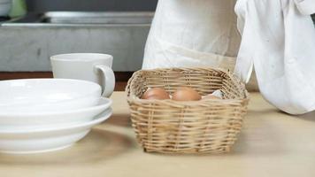 Chef stacks fresh eggs in basket on wooden table before cooking. video