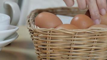 Chef stacks fresh eggs in basket on wooden table before cooking. video