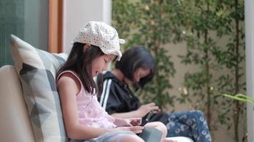 zwei asiatische Mädchen in einem lässigen Kleid, die Online-Spiele spielen. video