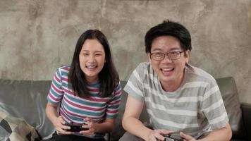 Hombre asiático divertido jugando consola de videojuegos con su novia. video