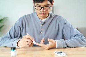 Man use lancet on finger for check blood sugar level by glucose meter photo