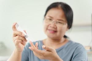 La mujer usa una lanceta en el dedo para controlar el nivel de azúcar en sangre con un medidor de glucosa. foto