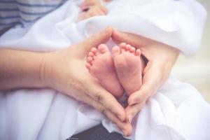 Mother holding newborn tiny and soft skin baby feet in both of hands photo