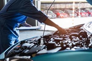 Car mechanic holding clipboard and checking to maintenance vehicle photo