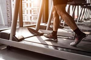 Close up of sport man running on treadmill in fitness gym photo