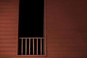 Balcón de madera con cuarto oscuro en la ventana. foto