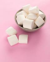 Marshmallow in bowl on pastel pink background photo