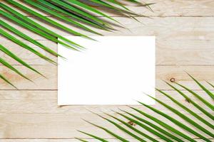 Vista superior de papel blanco vacío con hoja de palma en la mesa de madera foto