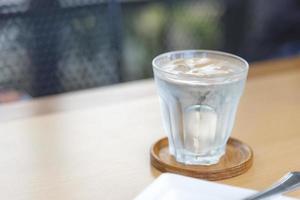 Agua mineral en vidrio sobre mesa de madera con fondo abstracto