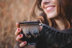 Beautiful woman smiles and holds a cup with a drink photo