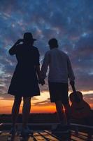 Silhouette of man with guitar and woman on roof of a car on sunset photo