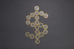 Signo de dólar hecho con monedas de plata brillantes con bordes dorados. foto