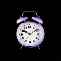 Reloj despertador de mesa púrpura clásico sobre un fondo negro