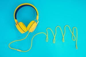 Yellow headphones or earphone computer on a blue pastel background