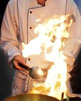 Chef cocinando con llama en una sartén sobre una estufa de cocina foto