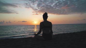 mujer meditando en la orilla de la playa video