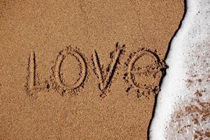 Word love on the beach is washed off with water photo