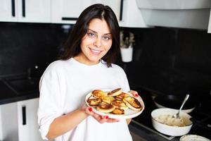 Mujer joven sostiene un plato de panqueques en sus manos foto