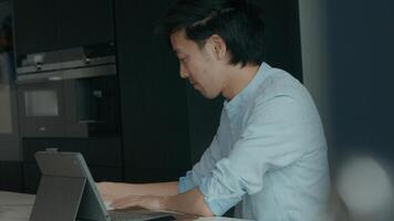 Man in kitchen with laptop looks up and shrugs photo