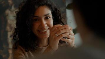 Woman sits and sips coffee whilst talking to man at table photo