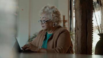 Woman sits at table typing on laptop photo