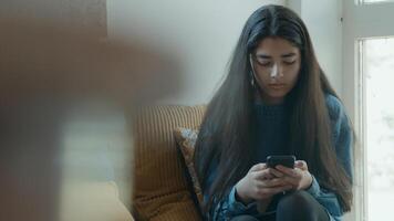 Girl sitting in corner looks at smartphone photo