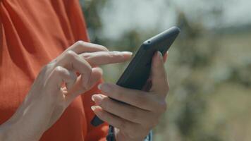 Hands of woman in green area typing on smartphone photo