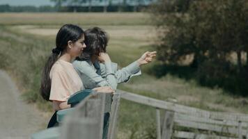 Woman and girl leaning on fence in the countryside talking photo