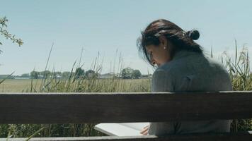 Woman sitting on wooden bench in the country reading a book photo