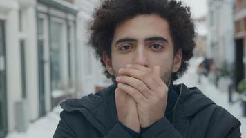 Close up of Middle Eastern man blowing warm air in hands photo