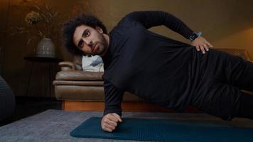 Young Middle Eastern man in living room, stretches fully, planking photo