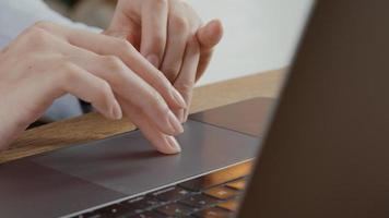 Close up of fingers of young woman moving on touch pad of laptop photo