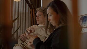 Two women watching television and smartphone on sofa photo