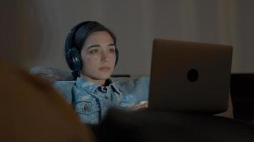 Woman on couch with headphone watching laptop photo
