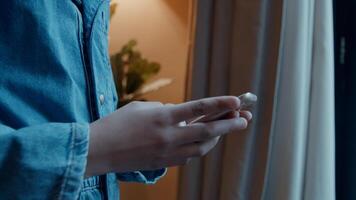 Girl standing typing on smartphone in front of window photo