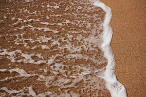 Sandy beach with a wave coming up photo