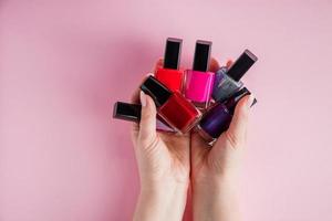 Hands with bright nail polishes. Group of colored nail enamel photo