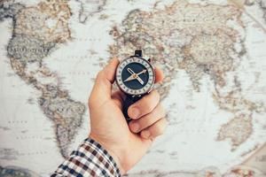 Man hold compass to check the direction with blurred map background photo